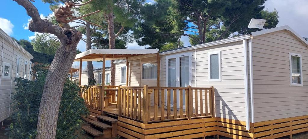 纳博讷普拉日Mobil Home (Clim, TV)- Camping Falaise Narbonne-Plage 4* - 003的一个小房子,设有门廊和甲板