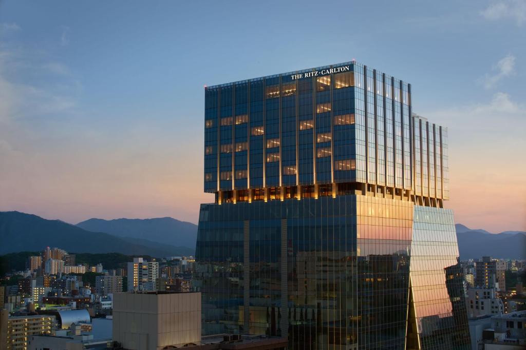 福冈The Ritz-Carlton Fukuoka的一座高大的玻璃建筑,以城市为背景