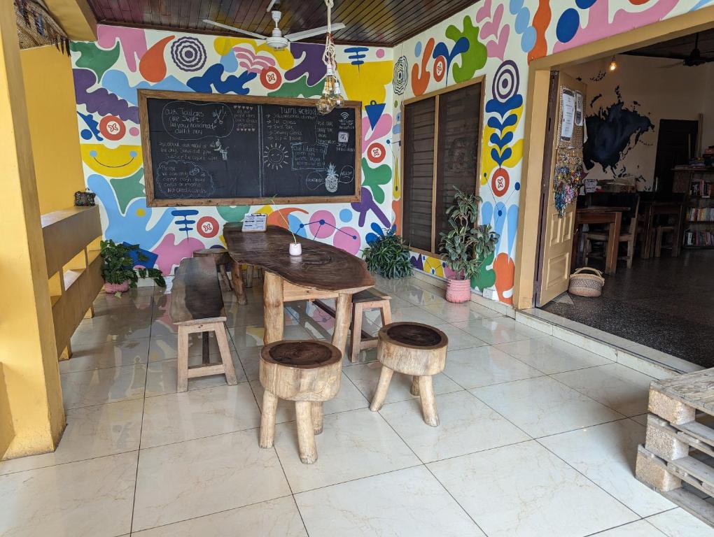 库马西Tumi Hostel的配有桌子、凳子和黑板的餐厅