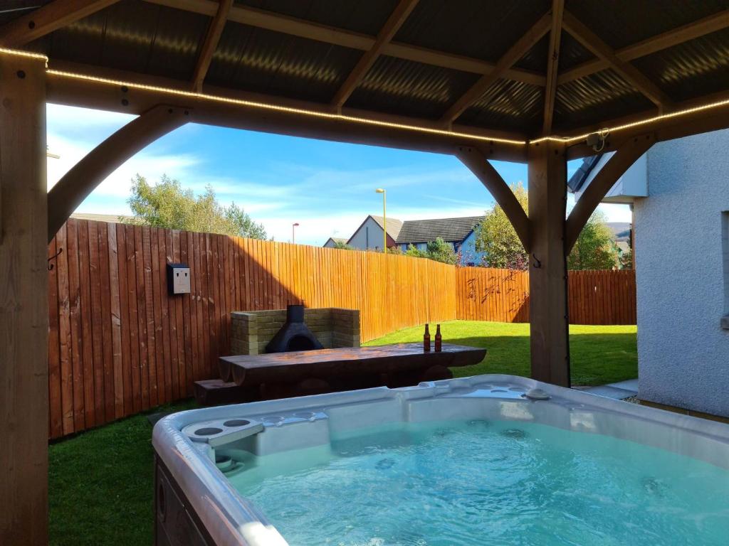 阿维莫尔Eagle Lodge - Aviemore Lodges的后院的热水浴池,设有木栅栏