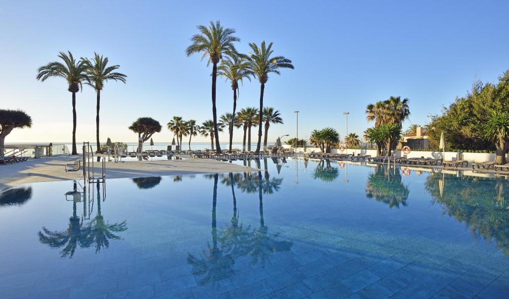 多列毛利诺斯Hotel Ocean House Costa del Sol, Affiliated by Meliá的一座棕榈树和海滩的大型游泳池