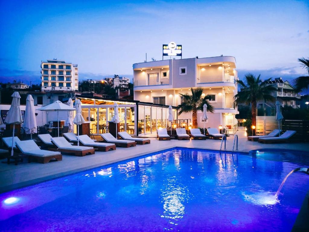 卡萨米尔Blue Water Hotel Ksamil的一座带椅子的大型游泳池和一座建筑
