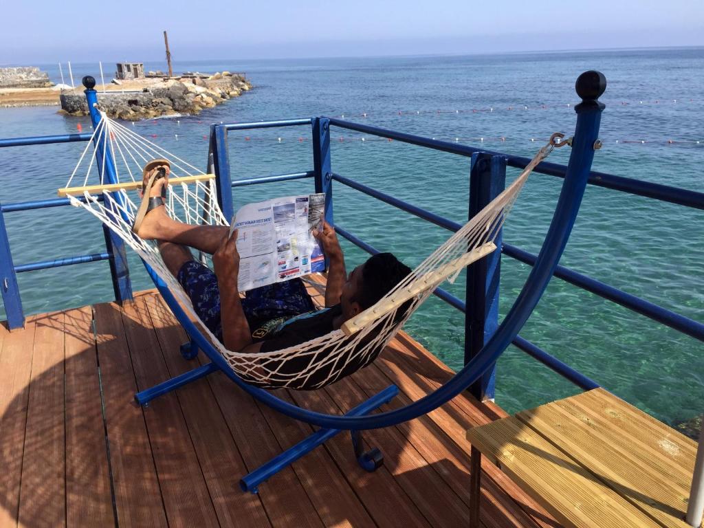 凯里尼亚马诺利亚酒店的躺在吊床上看报纸的人