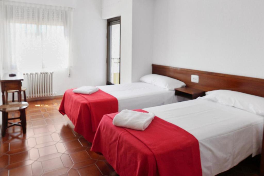 贝尼卡西姆Hostal La Torre的配有红色和白色床单的客房内的两张床
