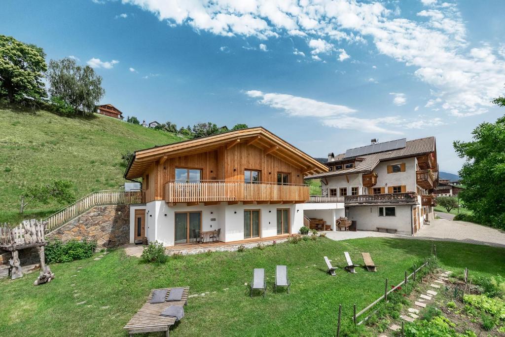 维兰德罗HAUSERHOF CHALET in Villanders - moderne Wohnungen mit 2 Badezimmer und 2 Schlafzimmer的一座带绿色庭院的山丘上的房子