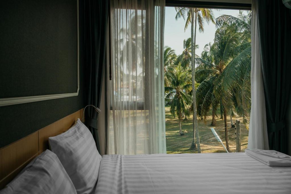 苏林海滩Phuket, Surin beach的一间卧室设有床铺和种有棕榈树的窗户。