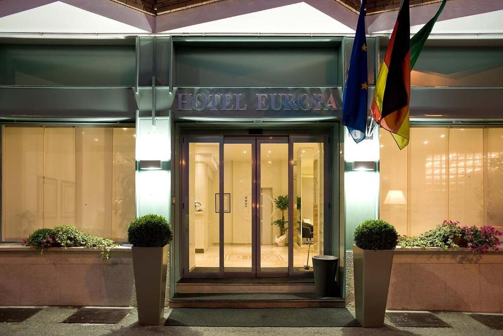 亚历山德里亚欧罗巴酒店的建筑的前门,有旗帜和植物