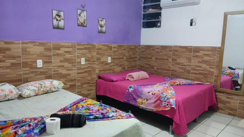 福塔莱萨Pousada Carimbó的紫色墙壁客房的两张床