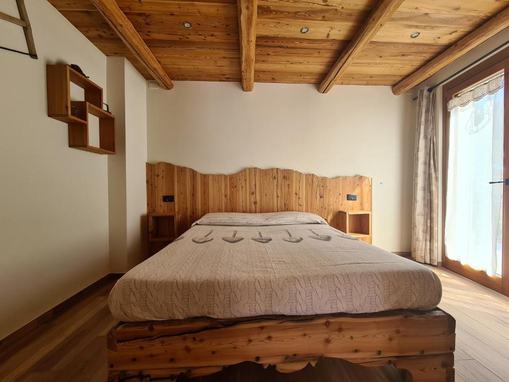 巴多尼奇亚La Maison. La Roccia dello Stambecco的一间带一张床的卧室,位于带木制天花板的房间内