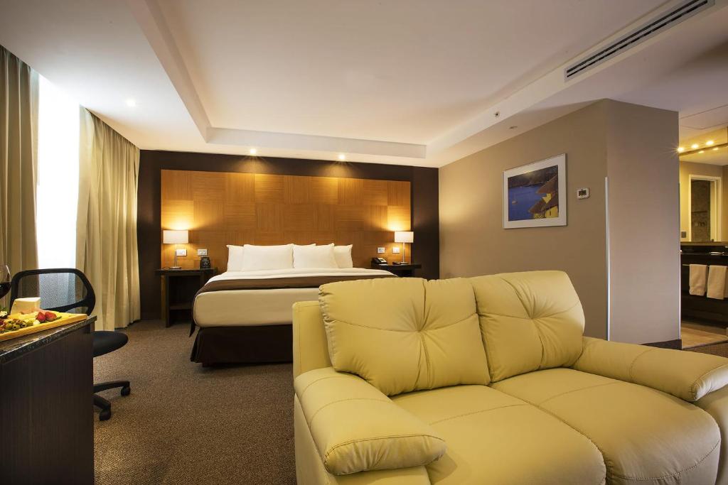 墨西哥城Krystal Urban Aeropuerto Ciudad de Mexico的酒店客房,配有床和沙发