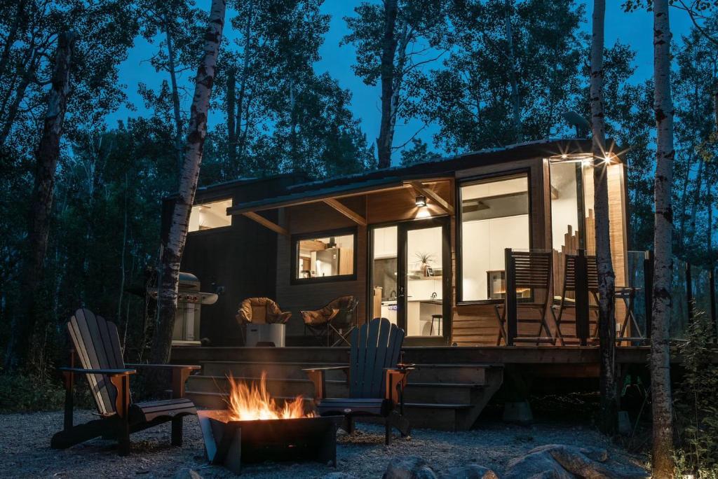 Refuge Bay's Aqua Tiny Home - Luxury Off Grid Escape的树林中的一个小小的房子,有一个火坑