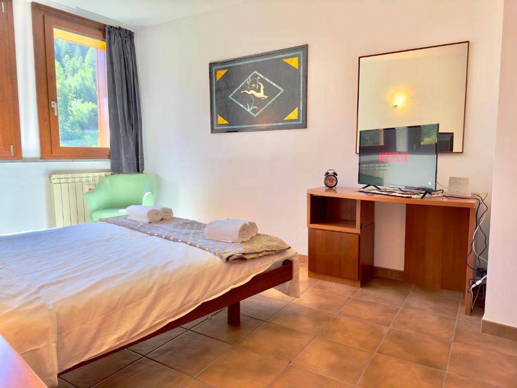 巴多尼奇亚[Paradiso di Montagna sulle piste da sci]的一间卧室配有一张床和一张书桌及电视