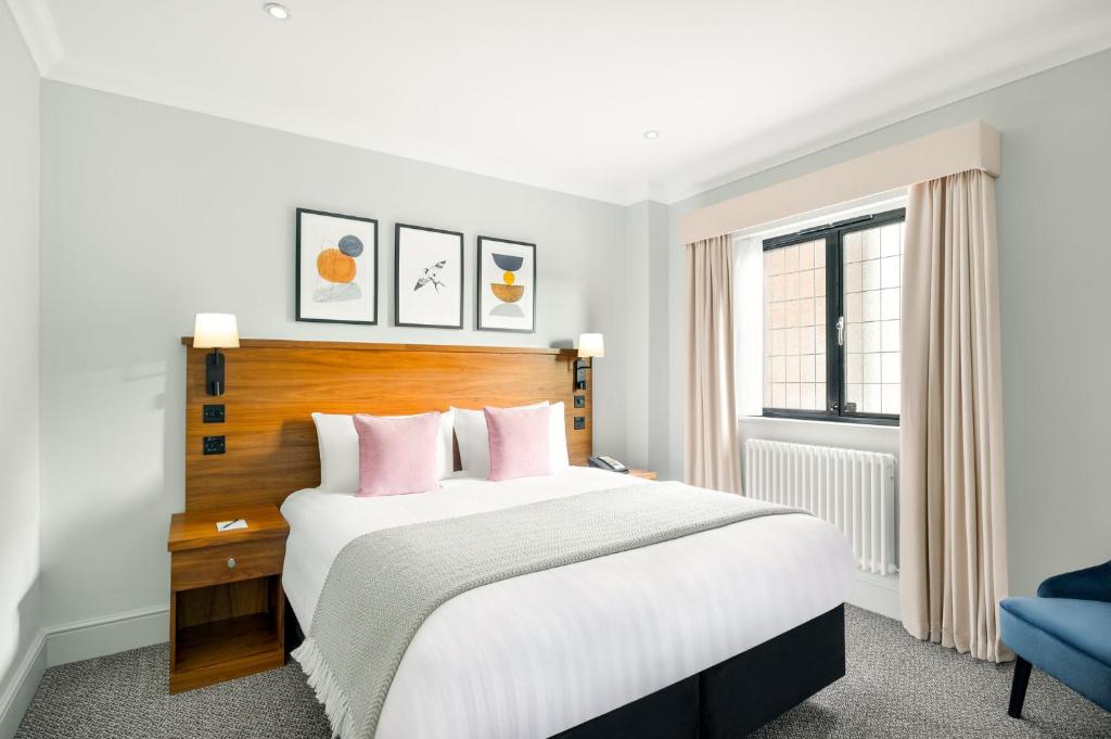哈斯尔米尔voco Lythe Hill Hotel & Spa, an IHG Hotel的卧室配有一张带粉红色枕头的大床