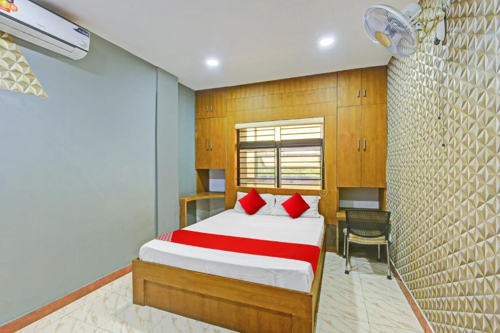 KondottiOYO Flagship Karipur Residency的一间卧室配有一张带红色枕头的床和一张书桌