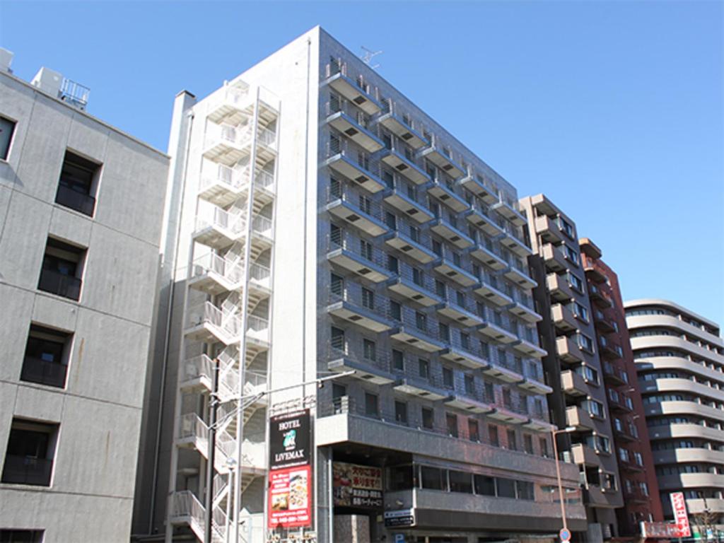 横滨HOTEL LiVEMAX BUDGET Yokohama Tsurumi的一条城市街道上高大的白色建筑