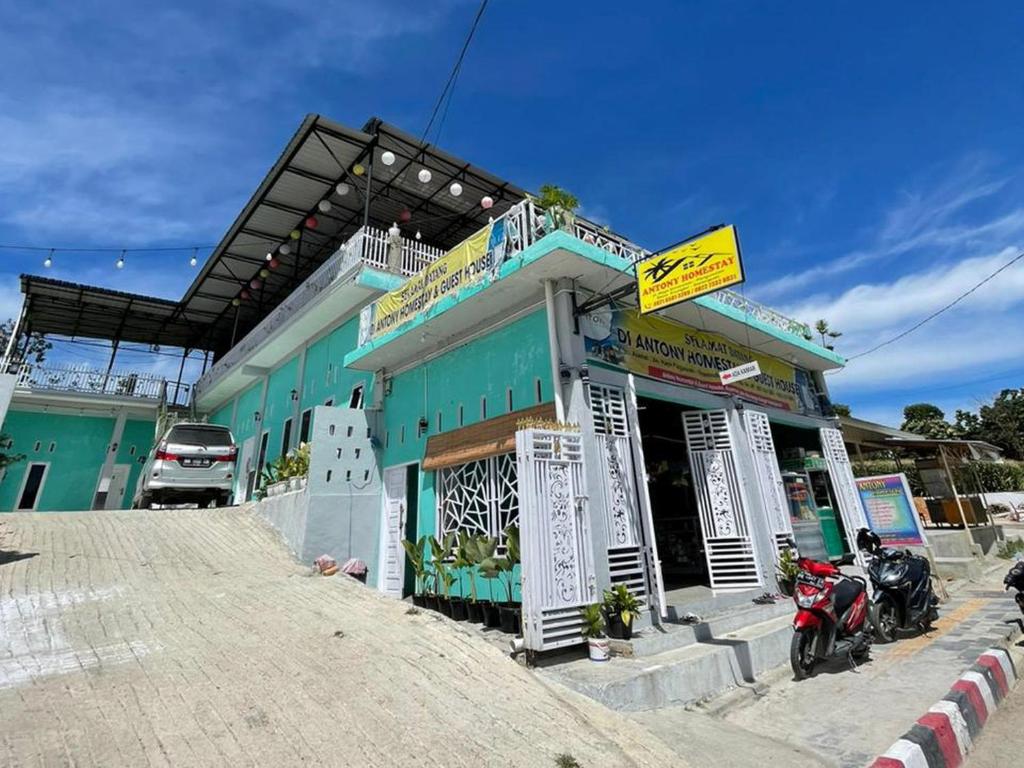 PangururanAntony Homestay near Pantai Pasir Putih Parbaba Mitra RedDoorz的一座蓝色的建筑,前面停有摩托车