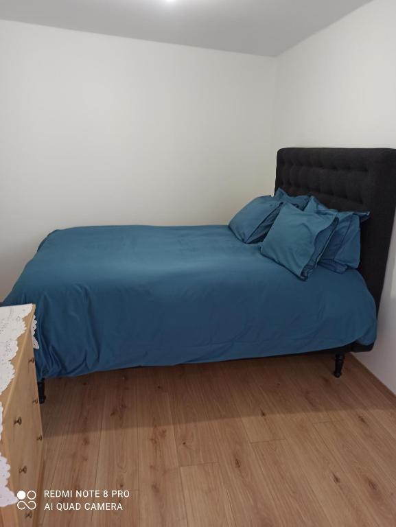 Saint-Front-la-RivièreLe Petit Cosy的一张带蓝色棉被和枕头的床