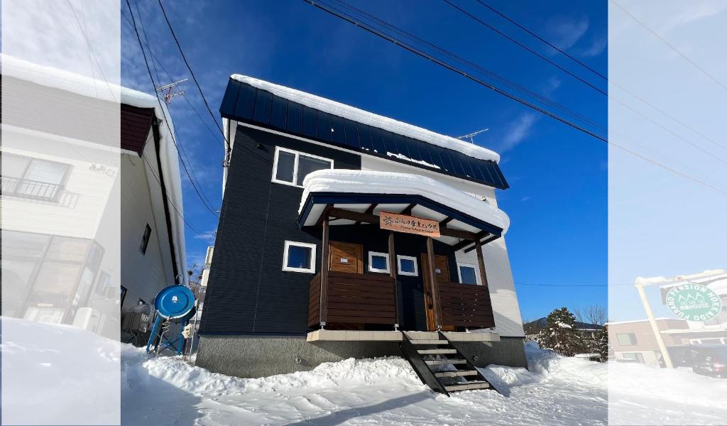 富良野Furano Yukisachi House的一座小建筑的侧面有雪