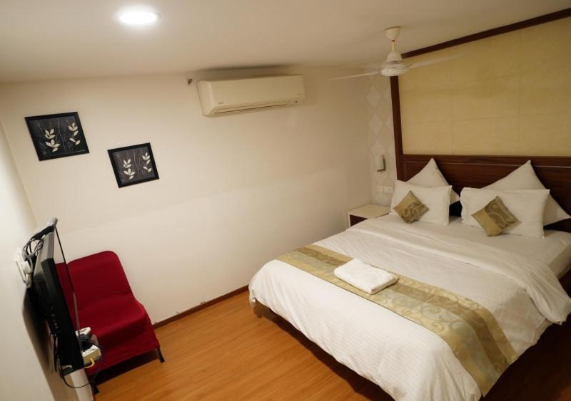 卡努尔Hotel Sasya Pride的一间卧室配有一张床和一张红色椅子