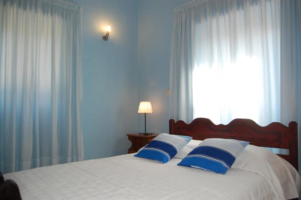 KorakádesVilla Korakades的一张带蓝色和白色枕头的床和窗户