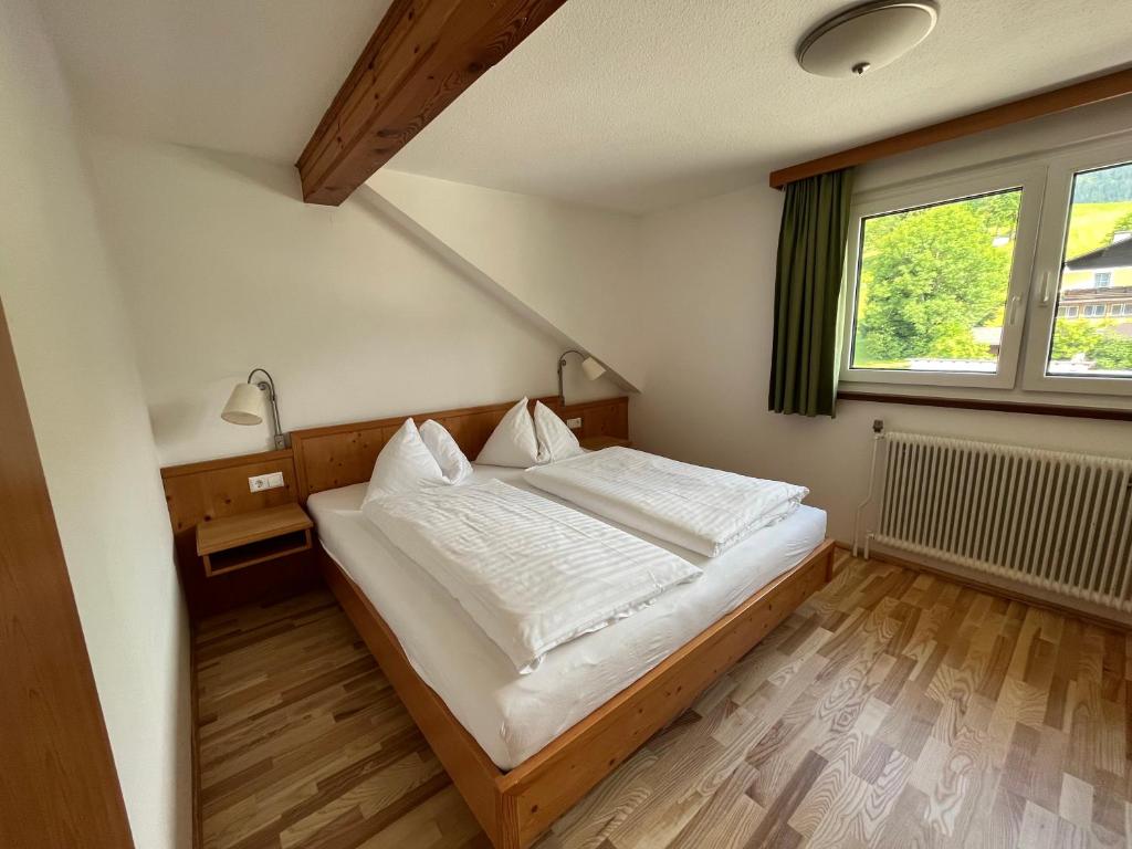 陶普利茨Appartements-Restaurant Schwaiger的一间卧室配有一张带白色床单的床和一扇窗户。