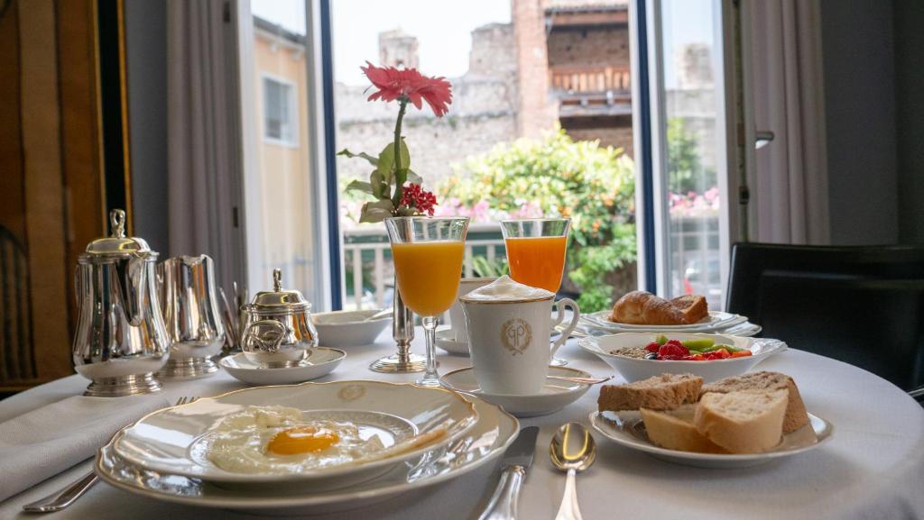 拉齐塞Hotel Villa Cansignorio的包括鸡蛋、面包和饮料的早餐桌