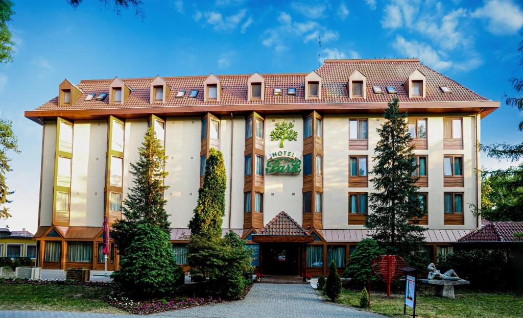 久洛Park Hotel Gyula的一座带红色屋顶的大型棕褐色建筑