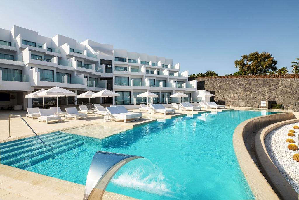 卡列罗港Royal Marina Suites Boutique Hotel的酒店设有带白色躺椅的游泳池