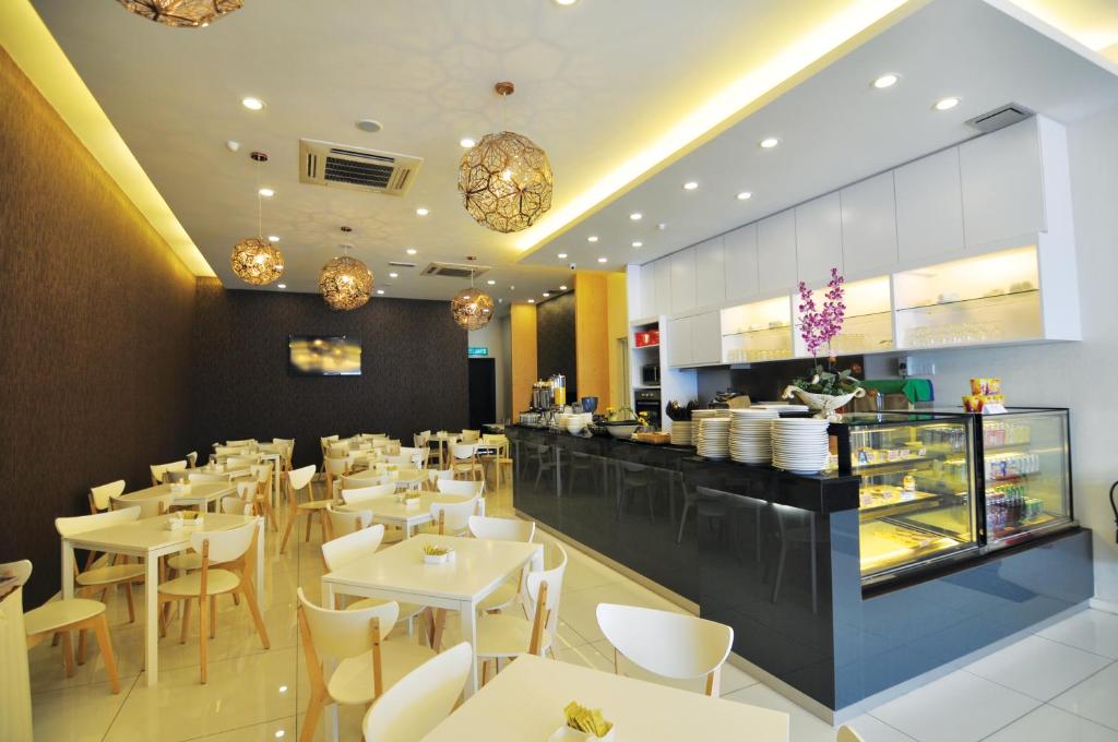 马六甲MIO BOUTIQUE Hotel的餐厅设有白色的桌椅和柜台