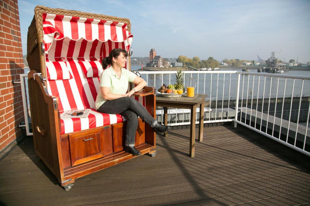 汉堡Hotel AM ELBUFER的坐在阳台的大摇椅上的女人