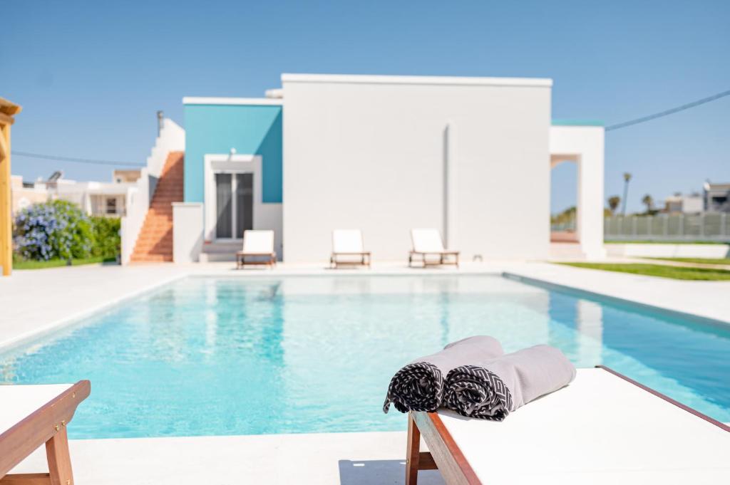 马斯蒂查里Villa Eos Mastichari - with heated pool的坐在游泳池旁椅子上的帽子和帽子
