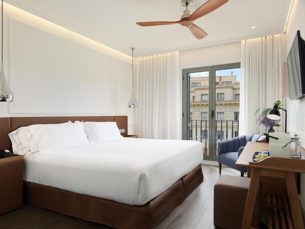 巴塞罗那H10大学酒店的卧室配有一张白色大床和一张书桌