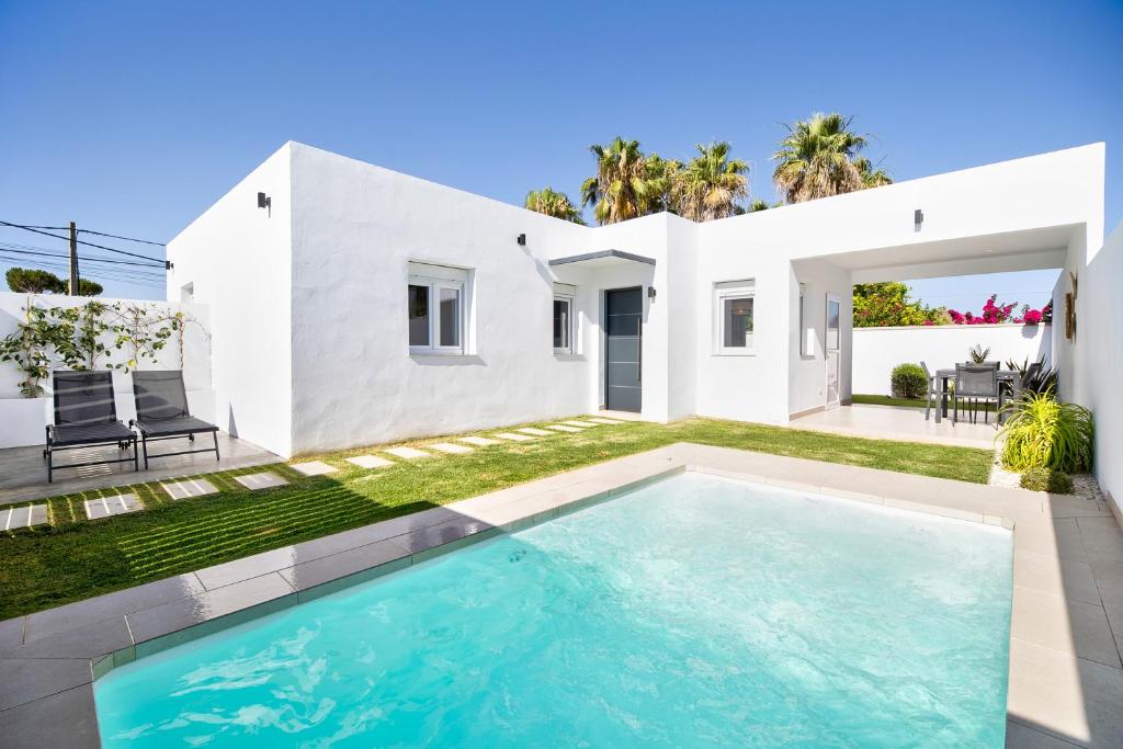 奇克拉纳－德拉弗龙特拉Casa Piscina Cubierta Climatizada 3的一座白色的房子,前面设有一个游泳池