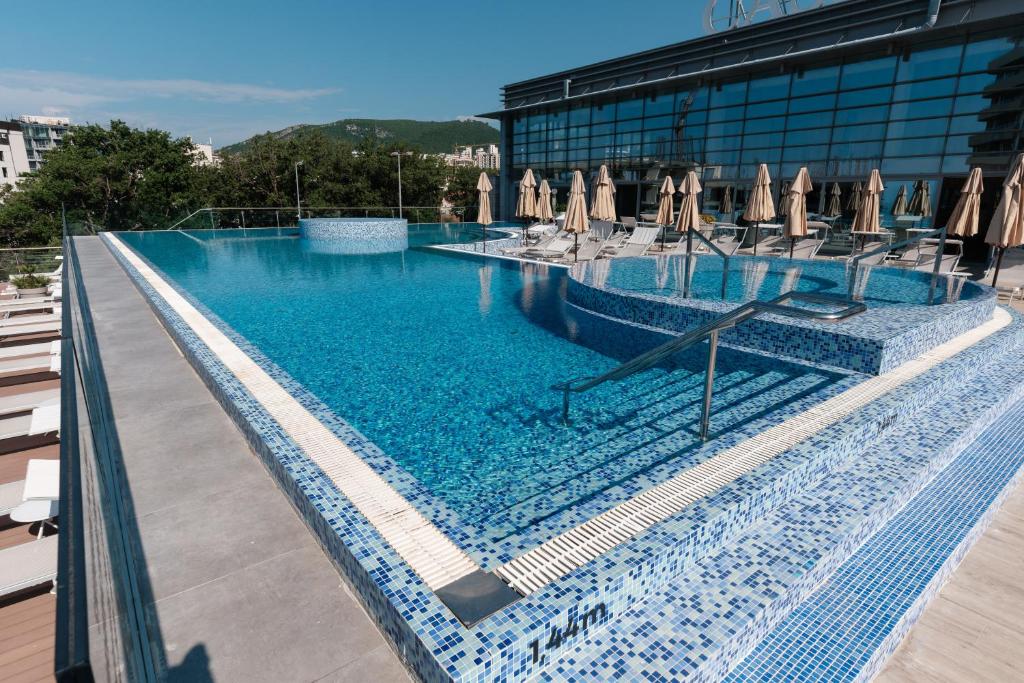布德瓦Eurostars Queen of Montenegro的一个带椅子和遮阳伞的大型游泳池