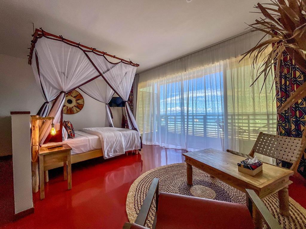 贝岛Maison Ylang Dive Center的一间卧室配有一张带桌子和沙发的天蓬床。