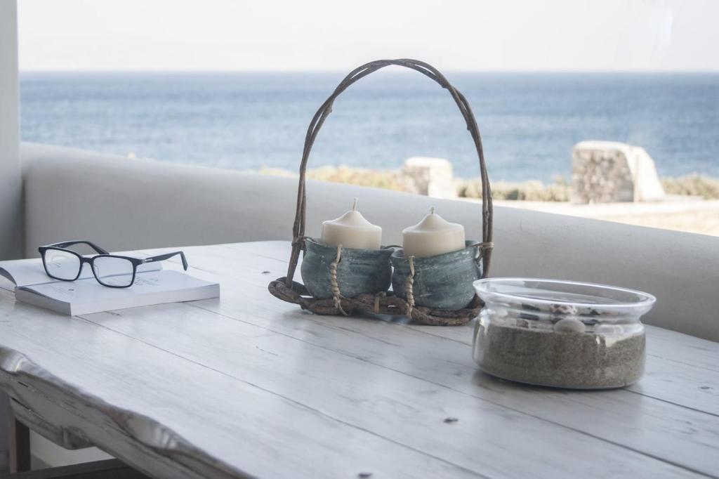 洛加拉斯Paros Melodia Apartments的桌子上摆放着眼镜和蜡烛,靠近大海