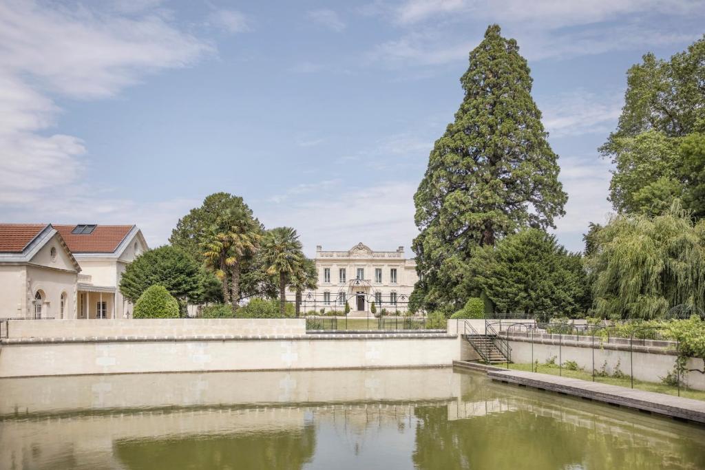 科涅克La Nauve, Hôtel & Jardin - Relais & Châteaux的享有凡尔赛宫的景色,设有池塘和树木