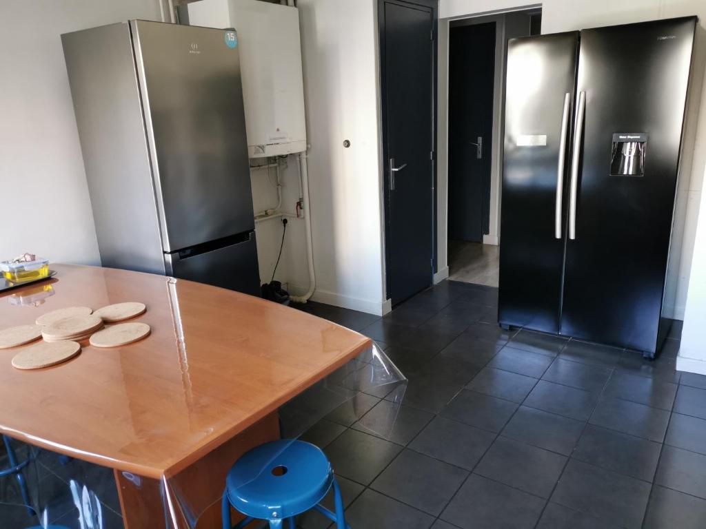 勒阿弗尔Résidence Zola的厨房配有木桌和冰箱。