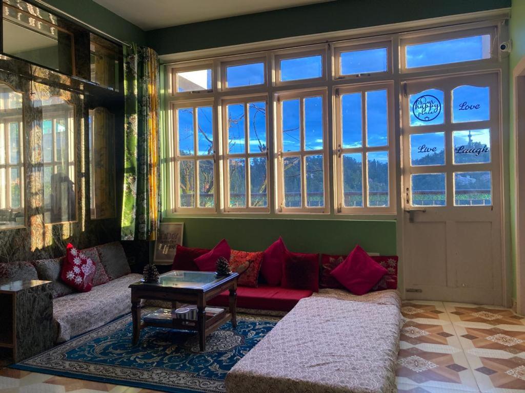 西姆拉Zu-Zu Hostels的带沙发和大窗户的客厅