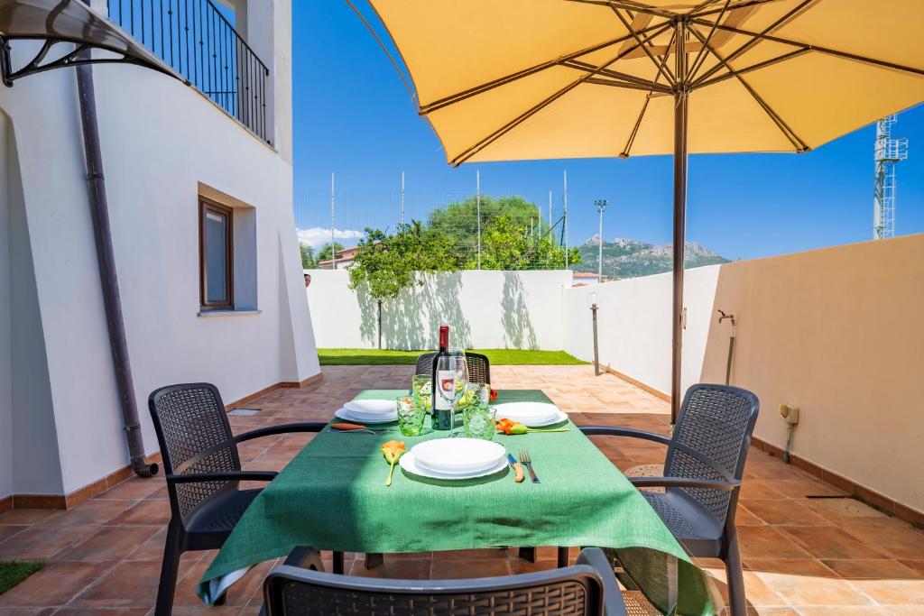 洛特佐拉伊5 - Relax e comfort in casa con giardino - Sa Crai Apartments Sardinian Experience的一张桌子,上面有绿桌布和黄伞