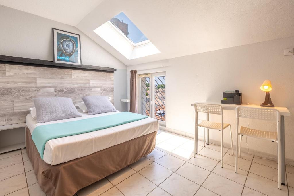 阿维尼翁科德利埃公寓酒店的卧室配有一张床和一张桌子及椅子