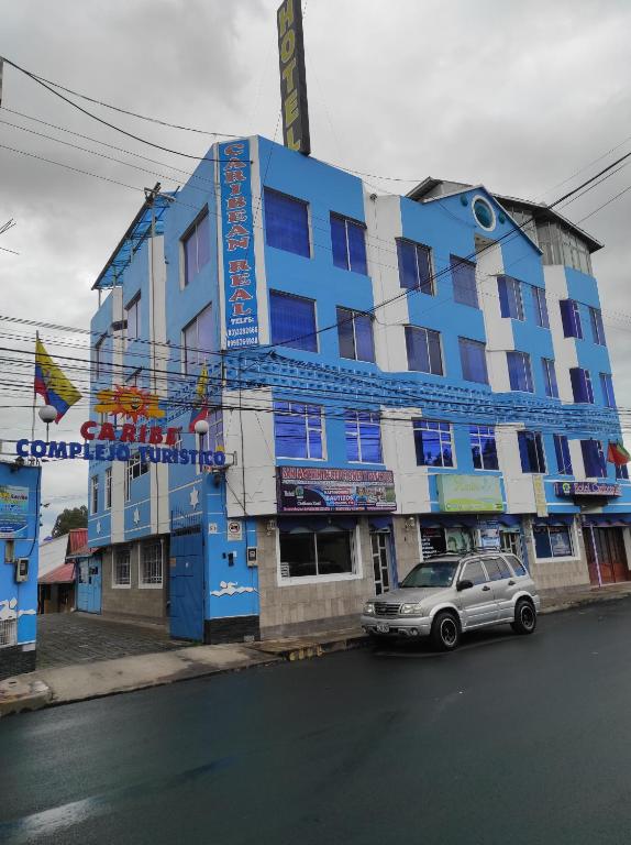 拉塔昆加HOTEL CARIBEAN REAL的蓝色的建筑,前面有停车位