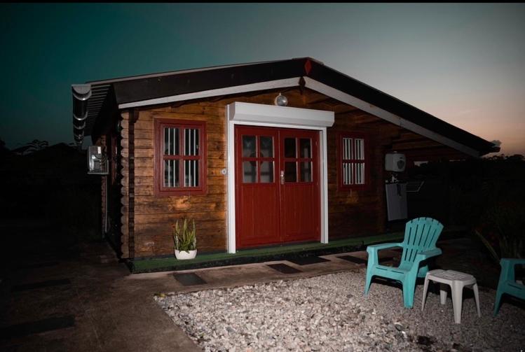 MatouryChalets BOISKANON A的一个带红色门和两把椅子的小小木屋