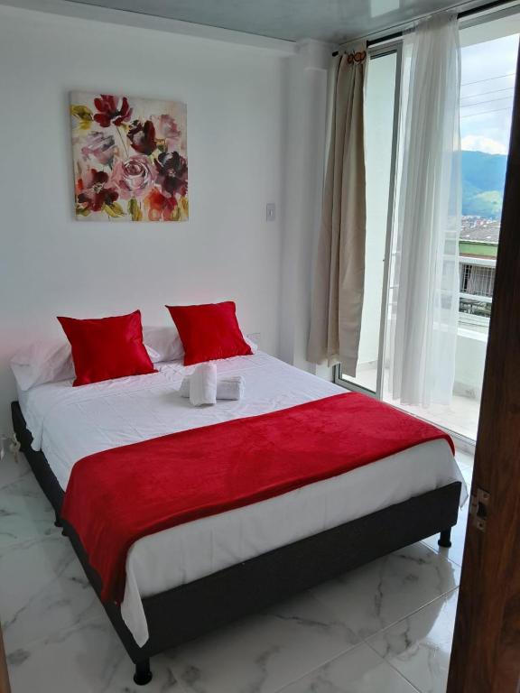圣罗莎德卡瓦尔Apartamento Amoblado en la via Termales Santa Rosa de Cabal的一间卧室配有一张带红色枕头的床和一扇窗户