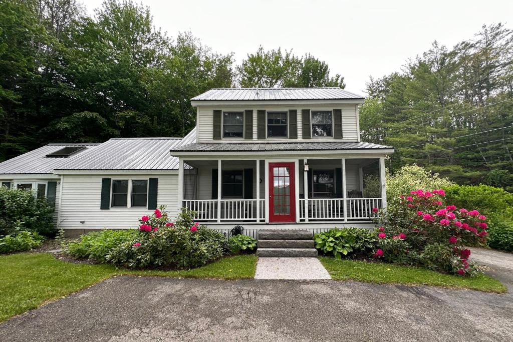 杰克逊Cottage at Green Hill的白色的房子,有红色的门和一些花