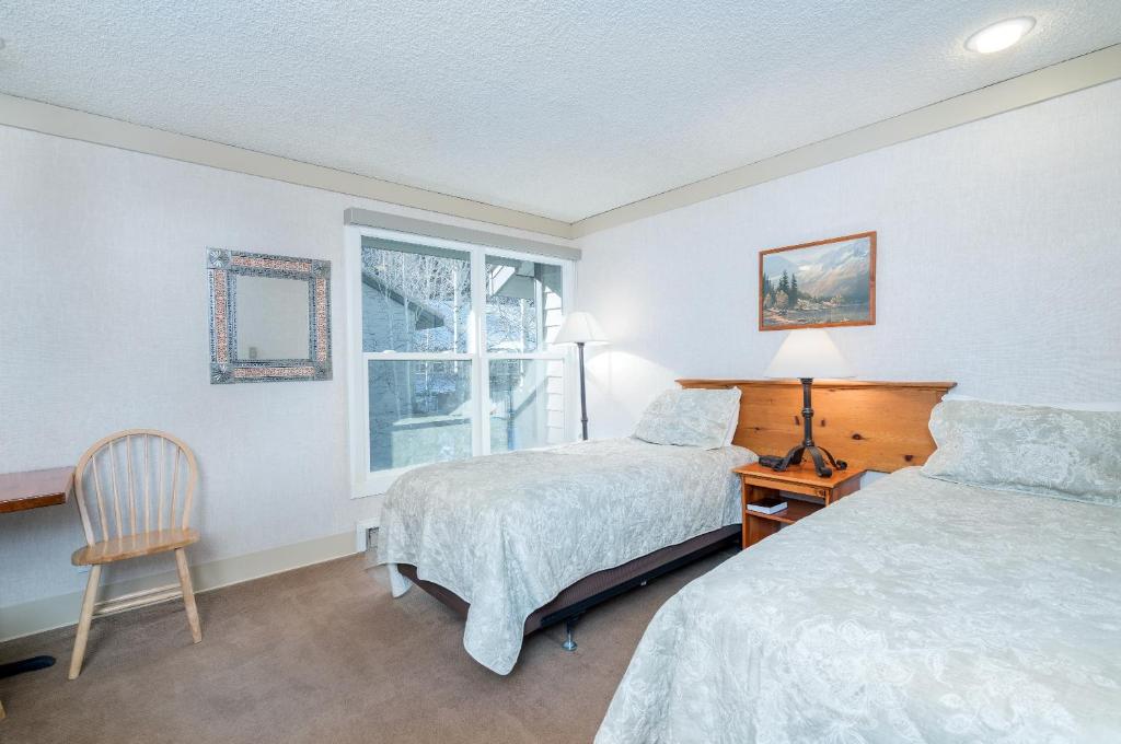 特柳赖德Mountainside Inn 218 Hotel Room的一间卧室设有两张床、一把椅子和一个窗户。