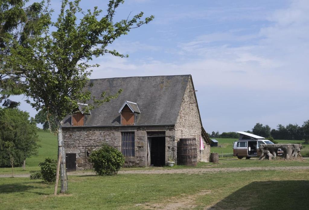 Le Ménil-CiboultLa Billardière Camping à la Ferme的一座古老的石头谷仓,一辆卡车停在田野里