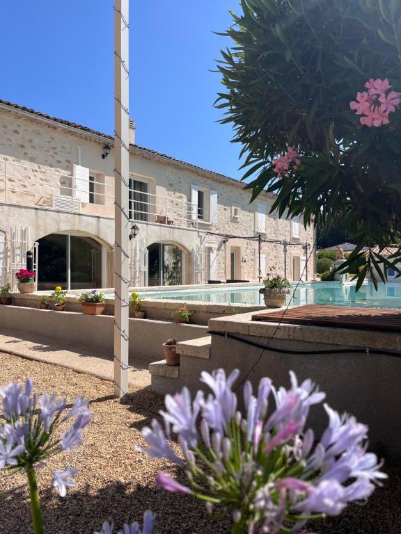 朗贝斯克Domaine Amourella的一座带游泳池和紫色鲜花的建筑