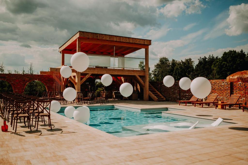 Stare MiastoSkansen Bicz Resort的一座带白色气球和椅子的游泳池以及一座建筑