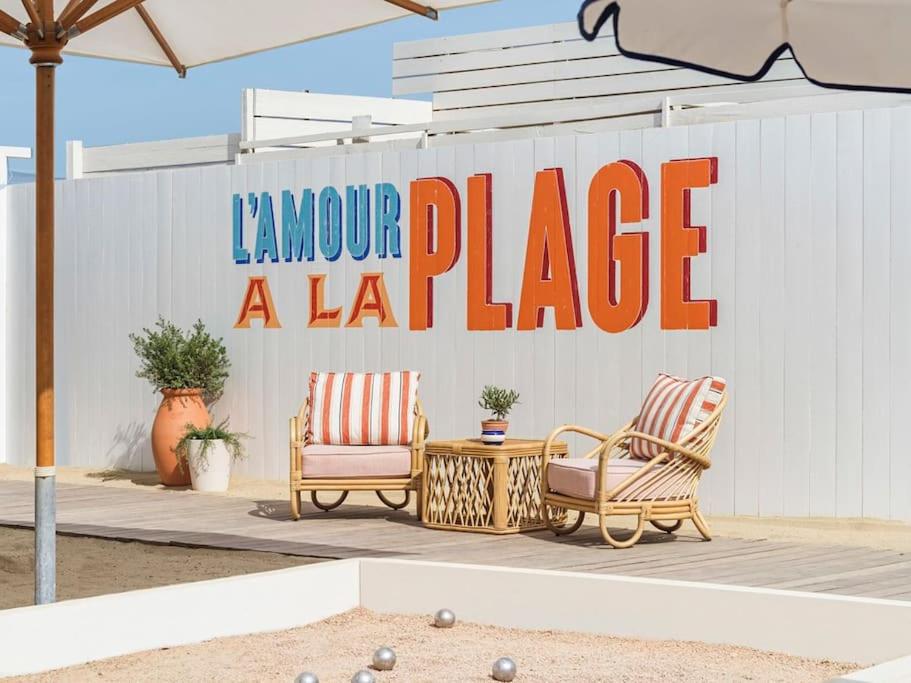 勒·雷约尔·卡纳德尔·苏尔Superbe, rénové, au calme, plage 200m, terrasse vue Mer!的两把椅子和一张桌子,在大标志前